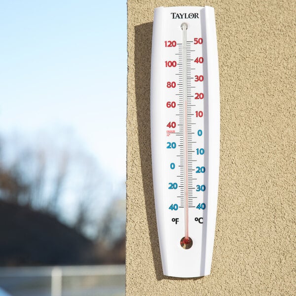 A Taylor wall thermometer with blue and white lines showing the temperature.