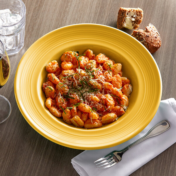 A Tuxton Concentrix saffron bowl filled with pasta on a table in an Italian restaurant.