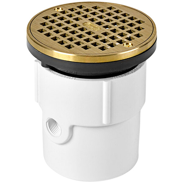 A white and brass Oatey PVC floor drain with a round strainer cover.