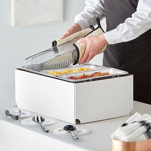 A person using a Choice chafer dish to prepare food on a table.