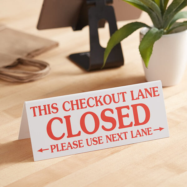 A "Checkout Lane Closed" sign on a table in a grocery store.