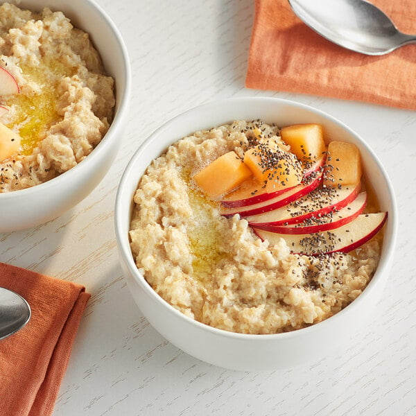 Two bowls of Bob's Red Mill gluten-free quick-cooking rolled oats with fruit slices on top.
