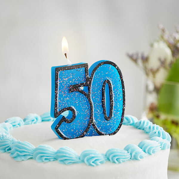 A white birthday cake with blue frosting and a blue "50" candle with glitter.
