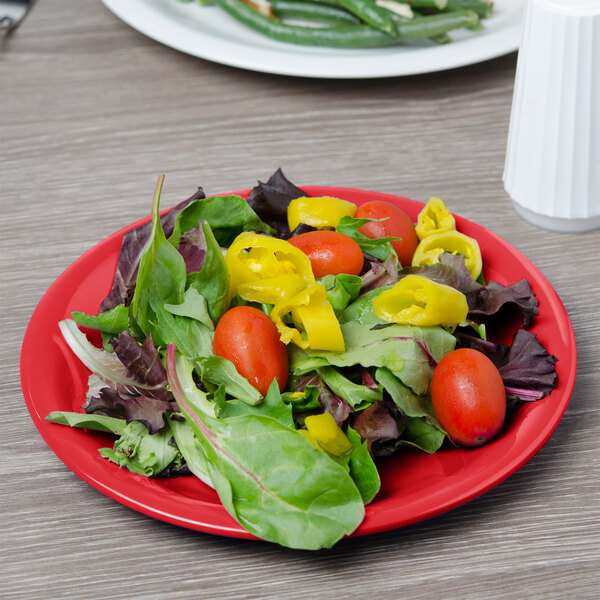 A red Carlisle Sierrus melamine salad plate with salad on it.