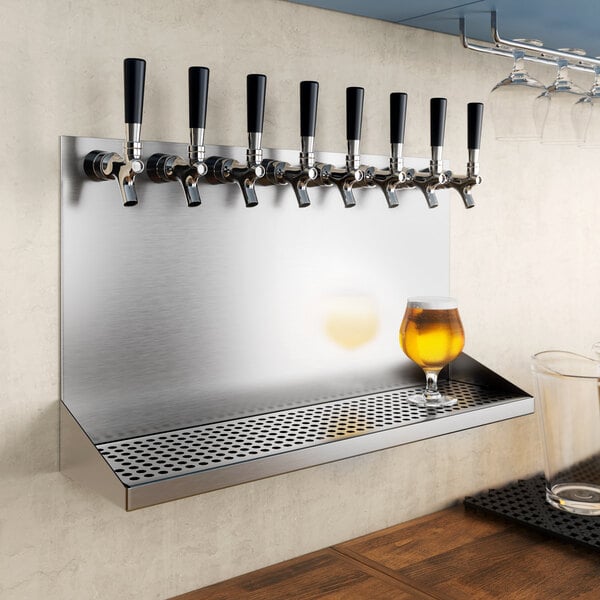 A row of beer taps on a Regency stainless steel wall mount beer drip tray.
