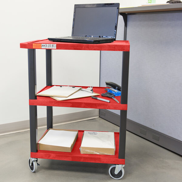 A red Luxor utility cart with a laptop on it.