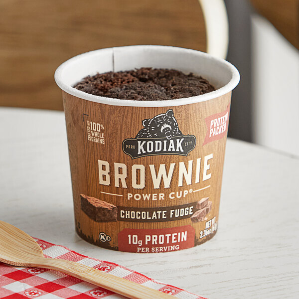 A brown Kodiak Cakes Chocolate Fudge Brownie cup on a white surface.