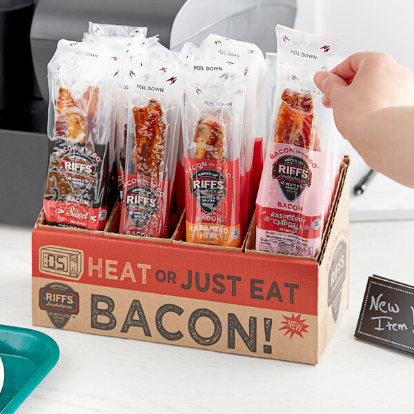 A person holding a package of Riff's Smokehouse Bacon On the Go with white, red, and black packaging.