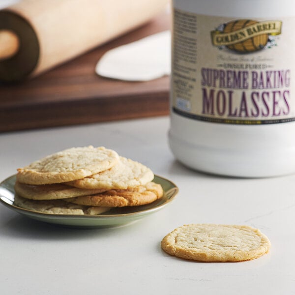 A plate of cookies next to a white jar of Golden Barrel Supreme Baking Molasses.