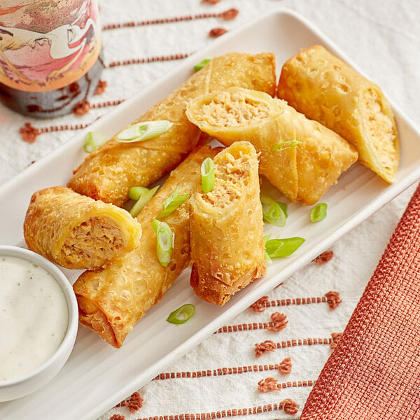 A plate of The Gourmet Egg Roll Co. Buffalo Chicken Egg Rolls with dipping sauce.