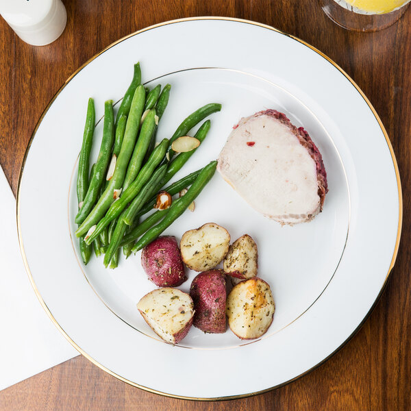 A CAC Golden Royal porcelain plate with meat, potatoes, and green beans on a table.