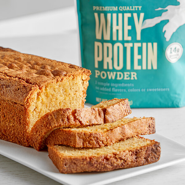 A loaf of bread on a plate next to a package of Bob's Red Mill Whey Protein Powder.