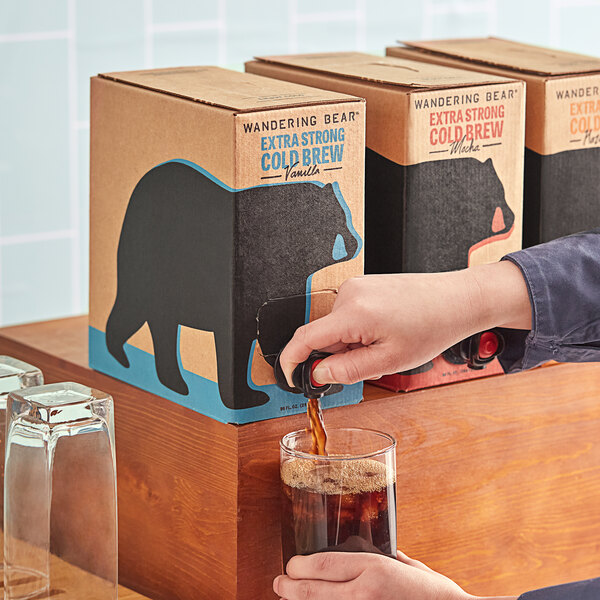 A person pouring Wandering Bear cold brew coffee into a box with a bear on it.