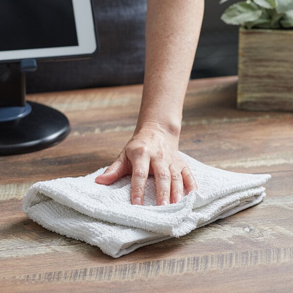 A hand wiping a white Choice bar mop towel.