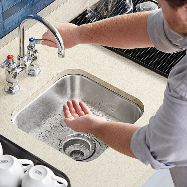 A person washing hands in a Waterloo stainless steel undermount sink.