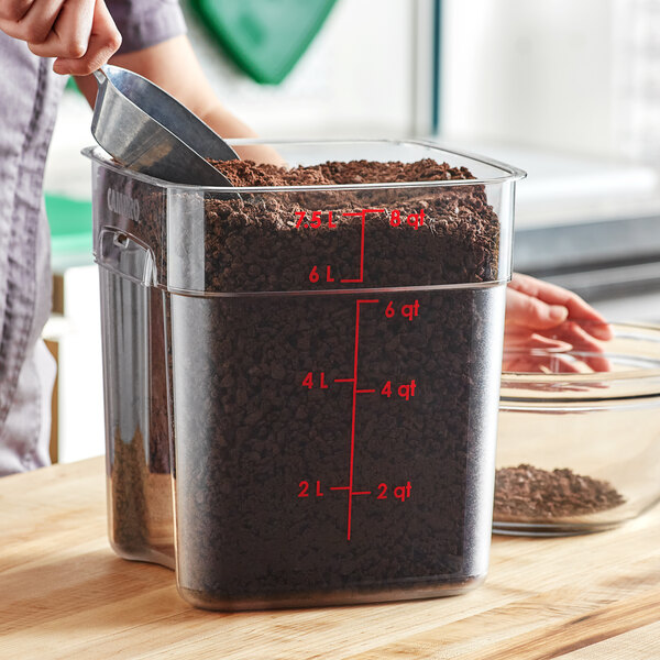 A person pouring dirt into a clear square container.