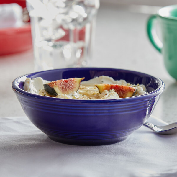 A Tuxton cobalt nappie bowl filled with yogurt and fruit on a table.