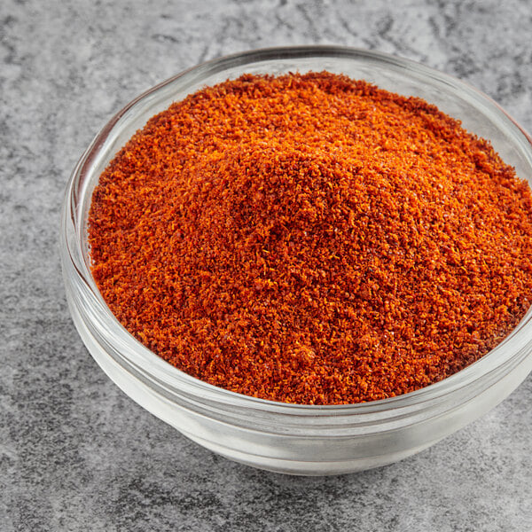 A bowl of McCormick Culinary Ground Cayenne Pepper on a gray surface.