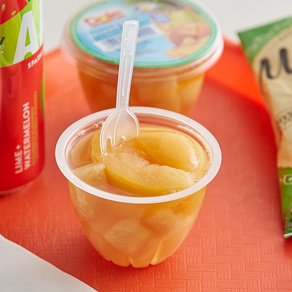 A plastic cup of Dole mixed fruit in juice with a spoon.