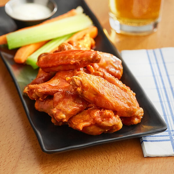 A plate of Frank's RedHot buffalo wings with celery sticks.