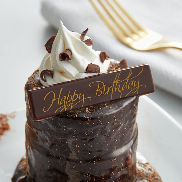 A chocolate cake with whipped cream and a Chocolatree Happy Birthday chocolate sign on top.