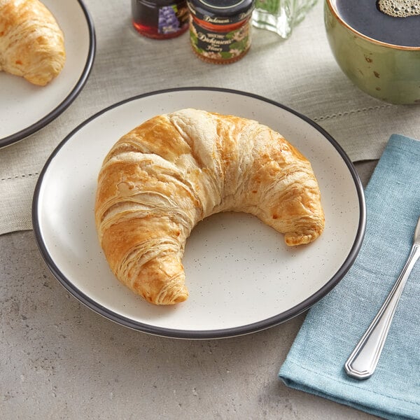 A Gourmand French butter croissant on a plate with a fork.