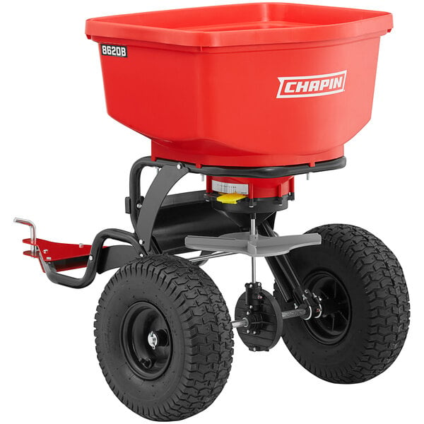 A red fertilizer spreader with wheels and a black handle.