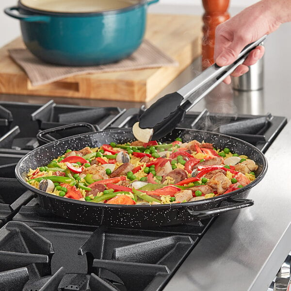 A Vigor enameled carbon steel paella pan of food on a stove.