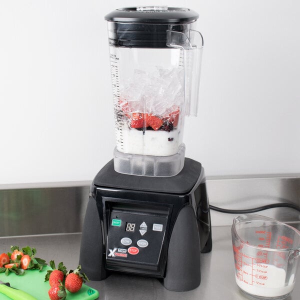 A Waring commercial blender with ice and strawberries in it.