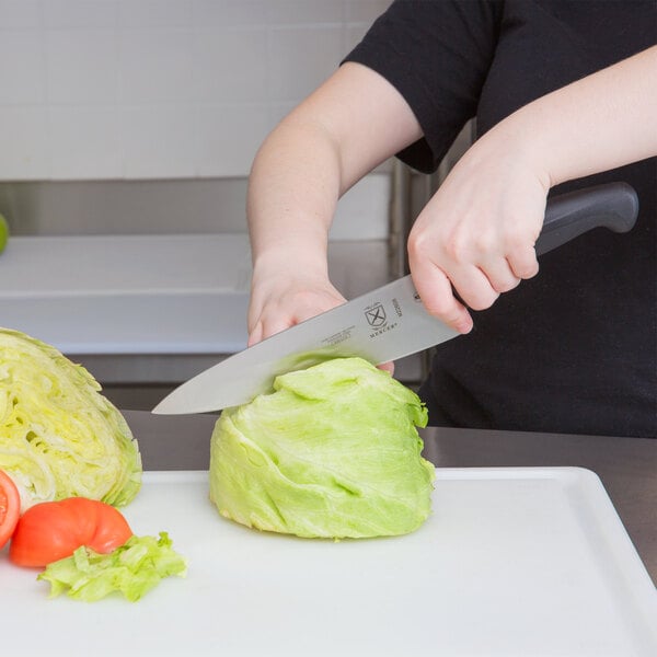 A person using a Mercer Culinary Millennia Chef Knife to cut cabbage.