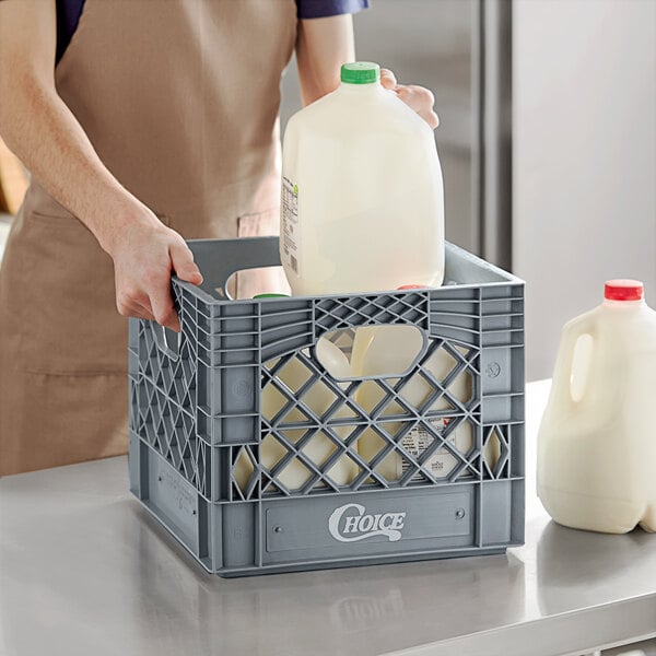 A person holding a Choice gray milk crate with a milk jug inside.