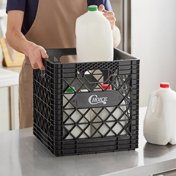 A man holding a white milk jug in a black Choice Super Crate.