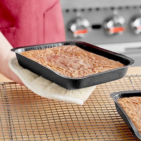 A person holding a tray of food in a Solut brownie pan.