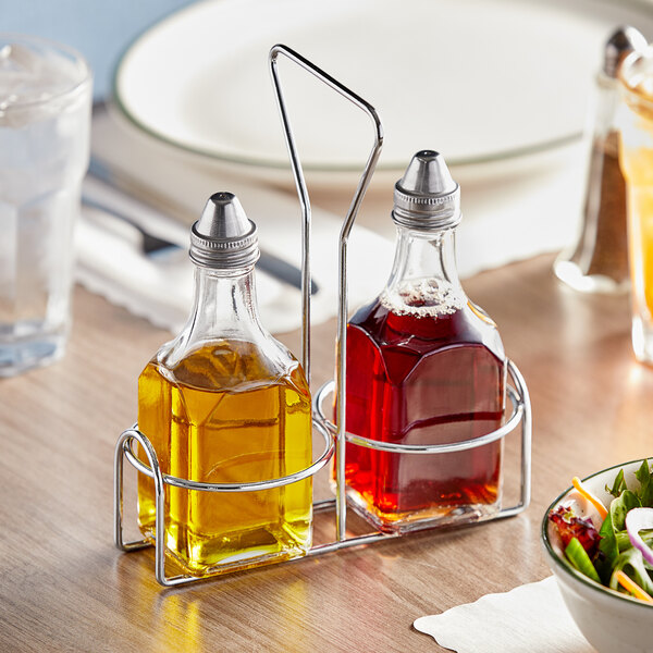 A wire caddy with a bottle of oil and a bowl of salad on a table.