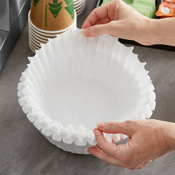 A hand holding a Choice paper coffee filter over a table.