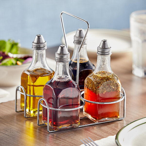 A white wire caddy holding four glass cruets filled with liquid.