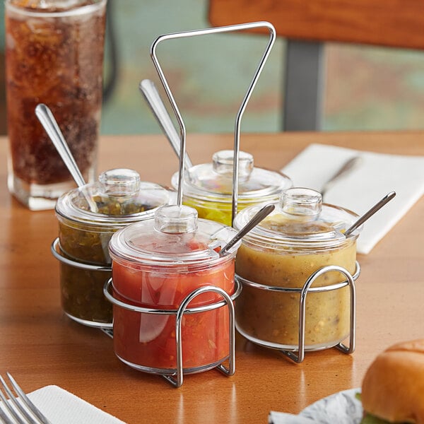 A Choice wire condiment caddy with clear plastic jars filled with different sauces on a table.