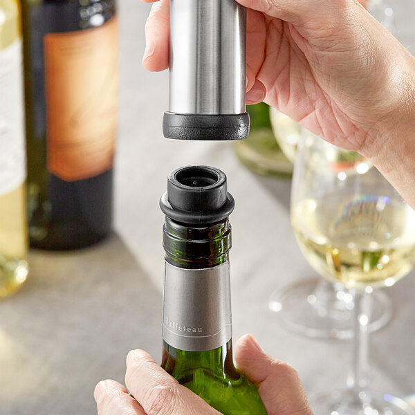 A person using an Acopa black wine stopper to close a bottle of wine.
