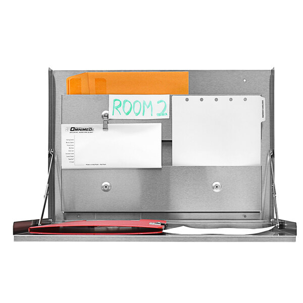 A stainless steel Omnimed wall desk with papers and a clipboard.