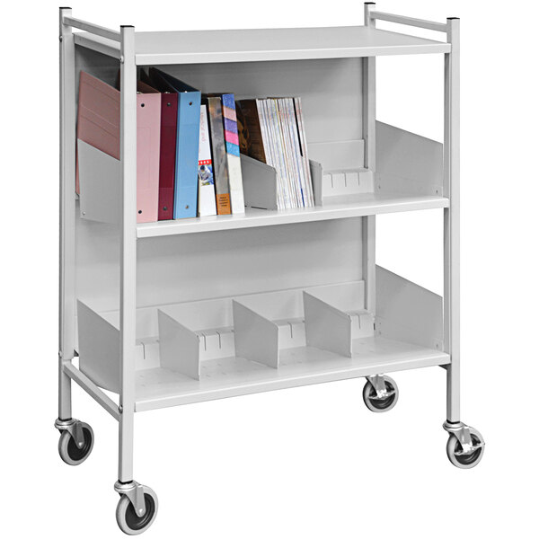 A white metal Omnimed Versa open style cabinet rack with books on it.