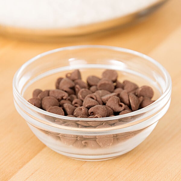 An Arcoroc glass bowl of chocolate chips next to a bowl of flour.