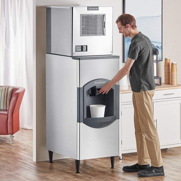 A man standing in front of a Scotsman ice machine and reaching for a water cooler spout.