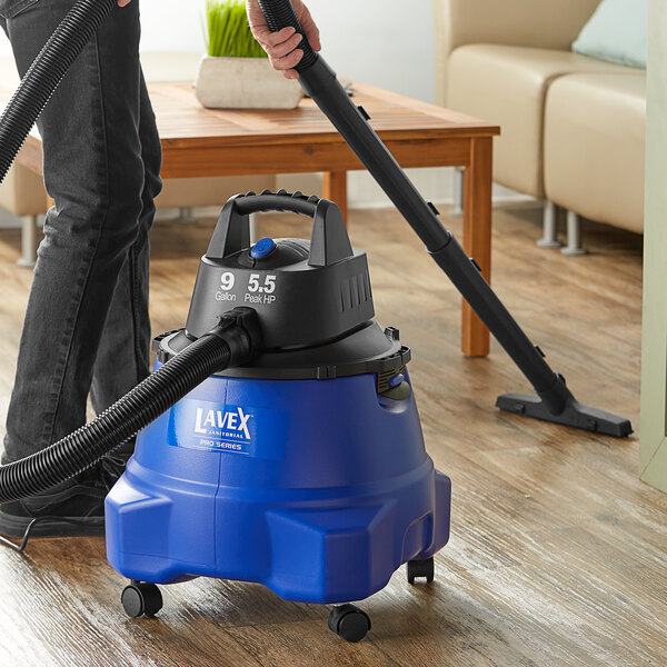 A man using a Lavex Pro wet/dry vacuum on a couch.