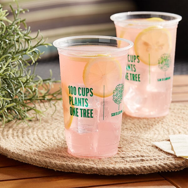 Two New Roots PLA compostable plastic cups with pink drinks and lemon slices on a table.