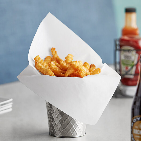 A silver cone basket filled with fries on a table.