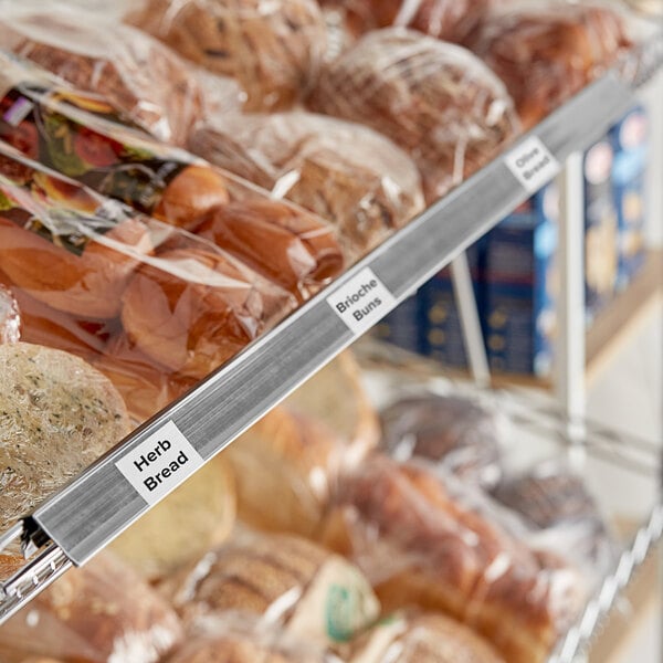 A shelf with a clip-on label holder and plastic-wrapped bread.