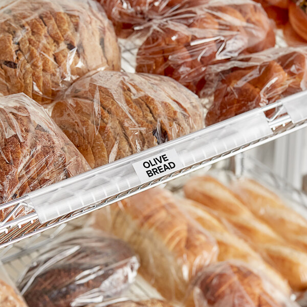 A shelf with bread in plastic bags, each with a clip-on label holder.
