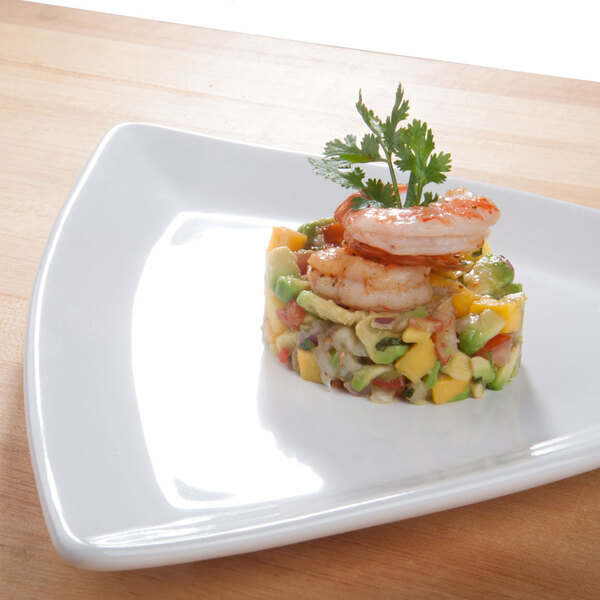 A Tuxton triangle eggshell china plate with shrimp and avocado salad on a table.