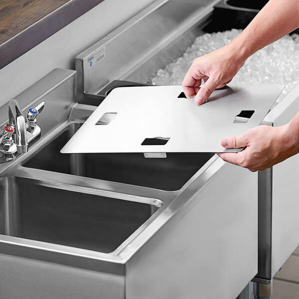A person using a Regency stainless steel sink cover to cut paper.