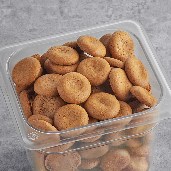 A plastic container of Homefree Gluten-Free Mini Ginger Snap Cookies sitting on a table.